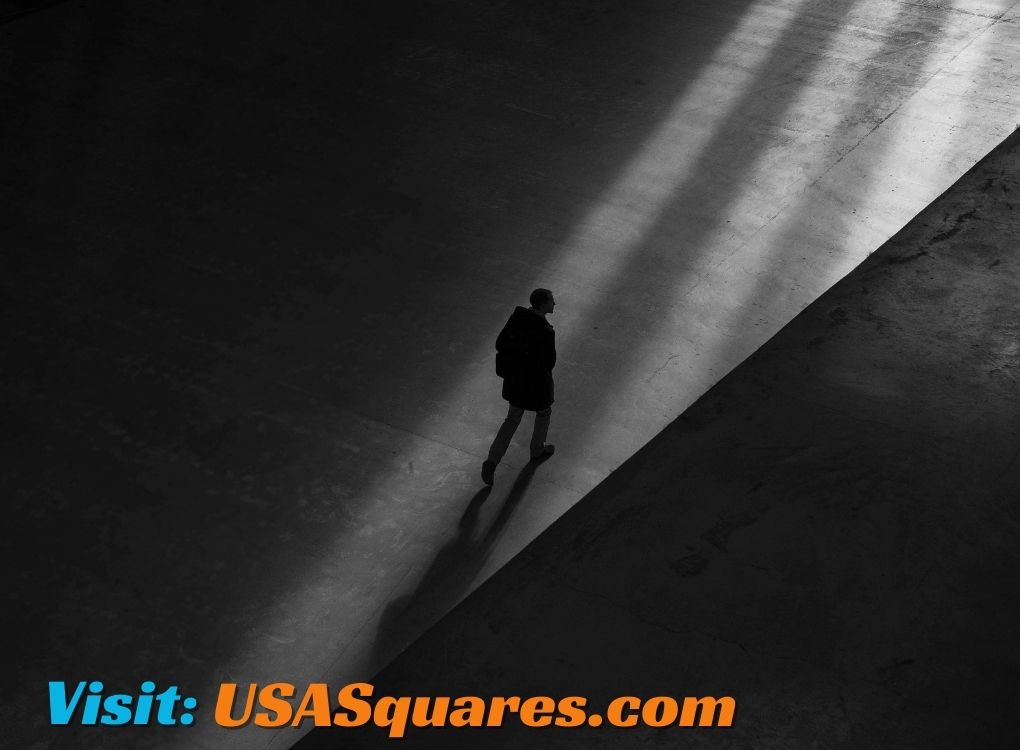 Silhouette of a person walking through a dramatic beam of light in a minimalistic black-and-white setting, with a call-to-action to visit USASquares.com.