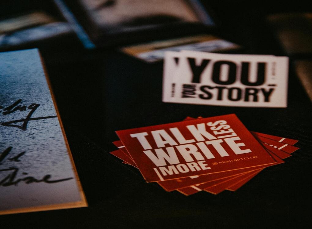 Motivational cards with text 'Talk Less, Write More' and 'Your Story' on a desk