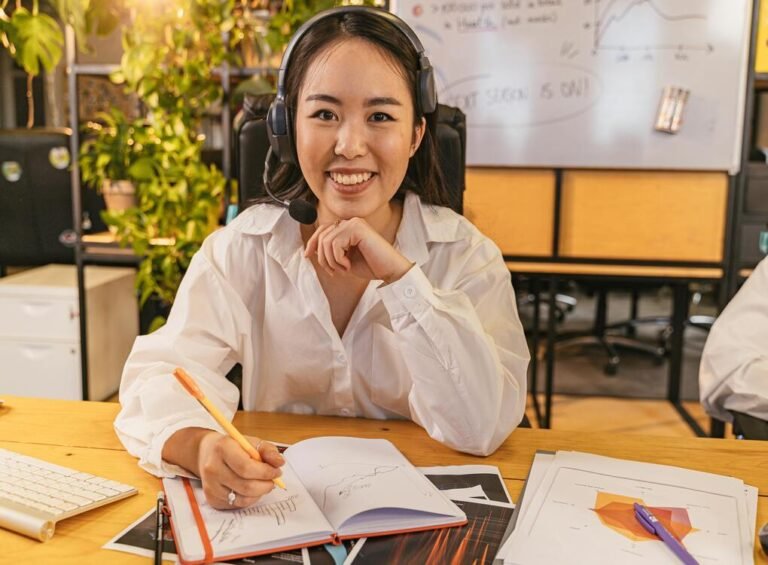 Young woman working on a project with headphones, notes, and charts at www.urbanwritingpros.com