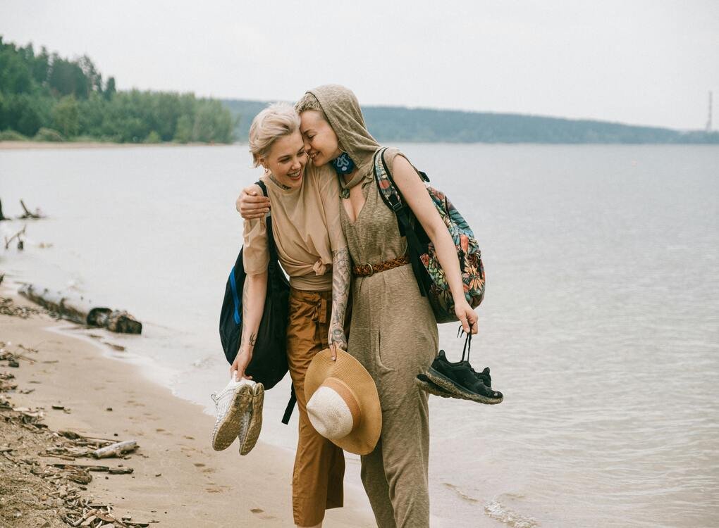 Two women walking along the beach, embracing and smiling, symbolizing themes from checwifeswap like trust, adaptability, and emotional bonds