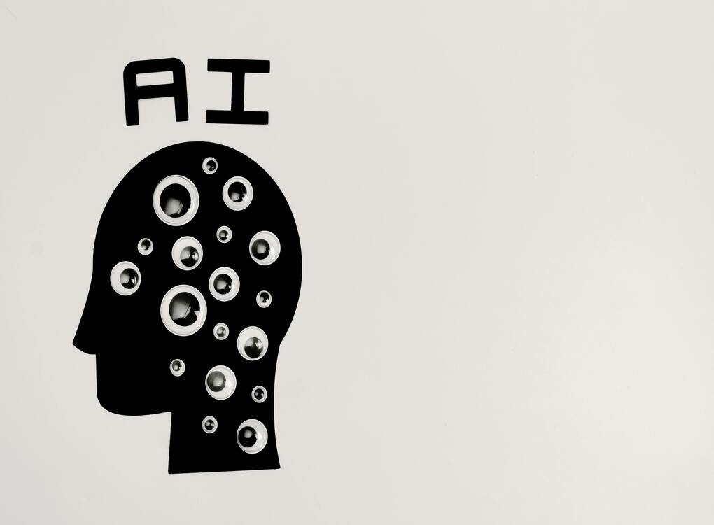 Silhouette of a human head with AI text and multiple eyes symbolizing artificial intelligence and data processing.