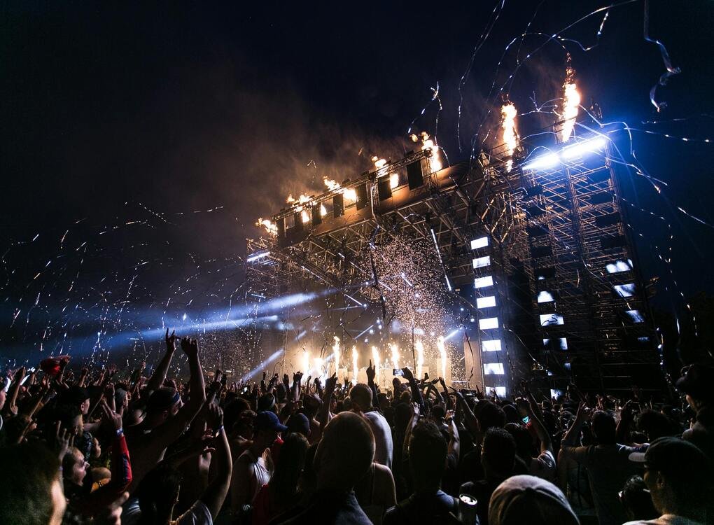 Fans cheering as fireworks and lights illuminate the stage during the Deep Purple fake farewell tour, capturing the unforgettable energy of the event