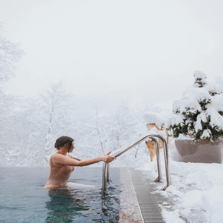 Winter pool enclosure featuring a heated swimming area surrounded by snow